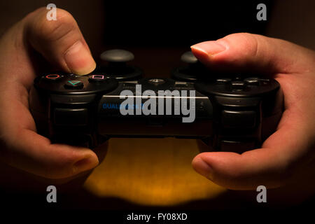 Due mani tenendo un wireless Sony Playstation Dual Shock 3 Controller mentre i pollici sono premendo i pulsanti Foto Stock