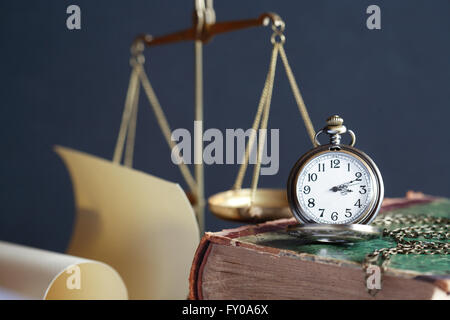 Vintage ancora in vita. Orologio da tasca sul vecchio libro vicino a scala di peso Foto Stock