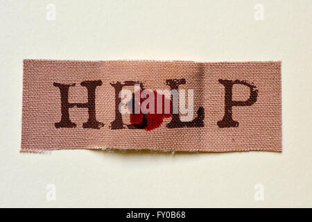 Primo piano di un tessuto bendaggio adesivo con una macchia di sangue e il testo di aiuto, su un fondo bianco Foto Stock
