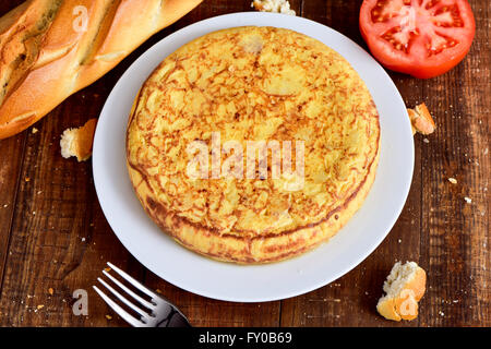 Ingrandimento di una piastra con una tipica la tortilla de patatas, una frittata spagnola, al buio su un tavolo di legno Foto Stock