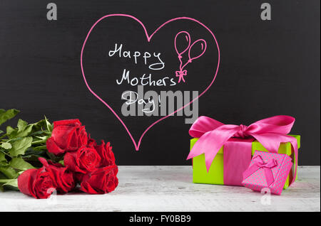 Felice Festa della mamma Composizione con rose rosse e rosa confezioni regalo su bianco tavola in legno rustico. Foto Stock