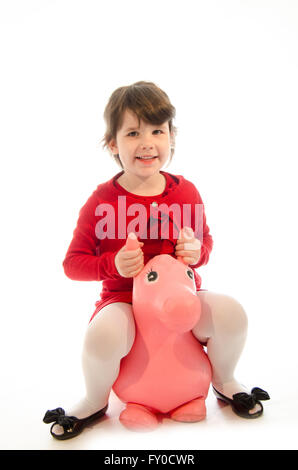 Dolce ragazza toddler giocando con un sontuoso cavallo giocattolo salti isolati su sfondo bianco Foto Stock