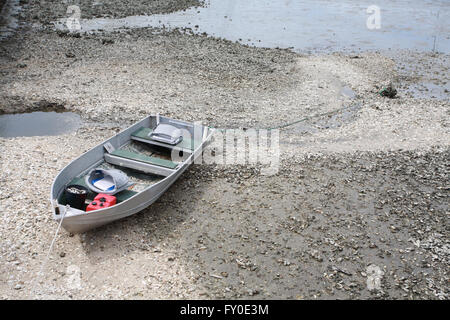 Una vecchia barca di alluminio legato ad una roccia sul lato atlantico riva del mare. All'interno della barca vi è un rosso di benzina in plastica o di benzina tan Foto Stock