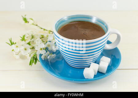 Il caffè con la fioritura dei ciliegi in una tazza di colore blu Foto Stock