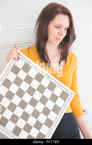 Donna seria azienda scacchiera in home interni. Concetto di strategia, le attività per il tempo libero e la contemplazione. Foto Stock