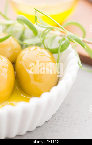 Olive verdi in olio di oliva e un rametto di timo fresco. Still Life foto di un aperitivo o uno snack. Foto Stock