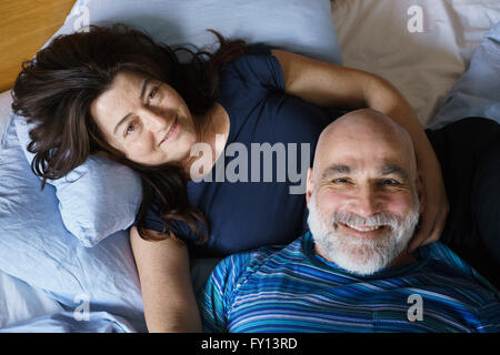 Angolo di Alta Vista della coppia matura giacente sul letto di casa Foto Stock