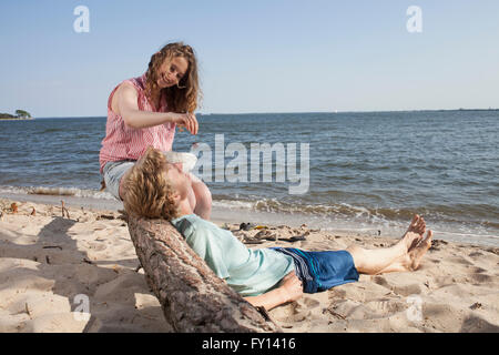 Donna sorridente ciliegia di alimentazione ad un amico durante i momenti di relax in spiaggia Foto Stock