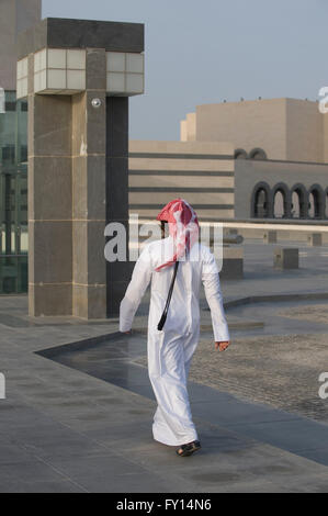 Vista posteriore del uomo arabo camminando sul pavimento contro edifici Foto Stock