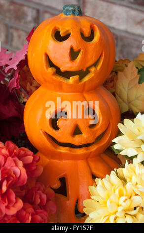 Una decorazione di 3 impilate jack-o-lanterne circondato da fiori Foto Stock