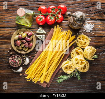Ingredienti per la pasta. Cherry-pomodori, spaghetti, rosmarino e spezie sul tavolo di legno. Foto Stock