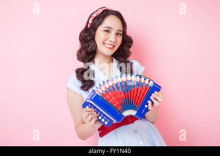 Ritratto di giovane donna sorridente in stile retrò di suonare la fisarmonica fissando sulla parte anteriore Foto Stock