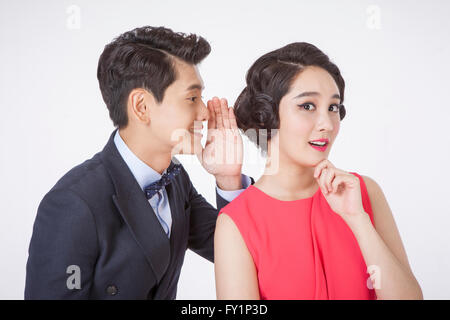 Ritratto di giovane coppia in stile retrò parlando in un sussurro Foto Stock