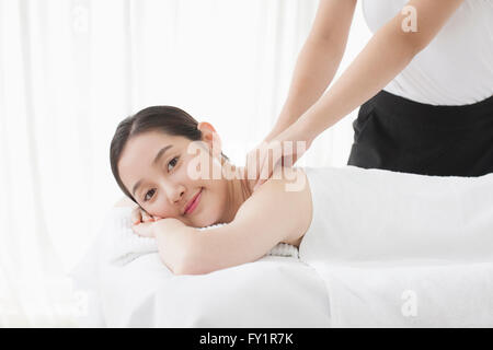 Vista laterale Ritratto di giovane donna getting massaggio della spalla fissando sulla parte anteriore Foto Stock