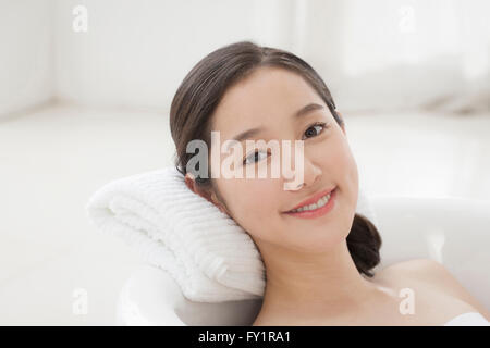 Ritratto di giovane donna sorridente di riposo in una vasca con lo sguardo sul lato anteriore Foto Stock