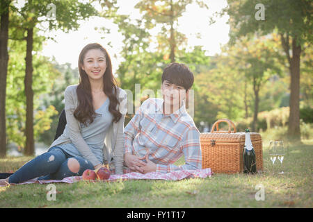 Giovane coppia sorridente avente un picnic al parco Foto Stock