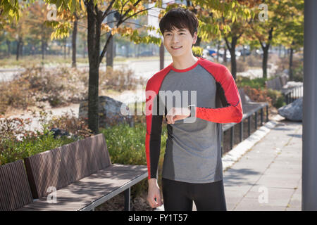 Giovane uomo sorridente indossando smart watch Foto Stock