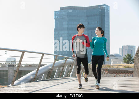 Giovane coppia sorridente jogging al parco Foto Stock