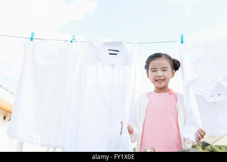 Ragazza con un servizio lavanderia appeso su una linea fuori e sorridente Foto Stock