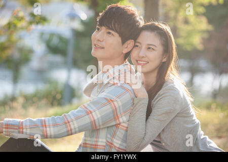 Donna appoggiata al suo ragazzo della spalla e sia con lo sguardo in alto con un sorriso a park Foto Stock