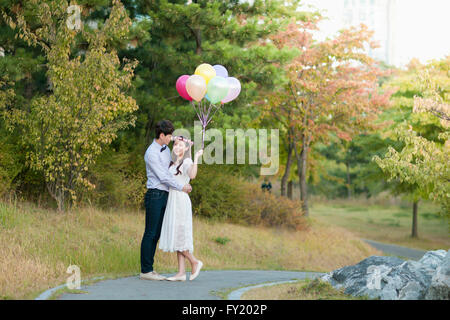 Sposa e lo sposo in piedi presso il parco con palloncini Foto Stock