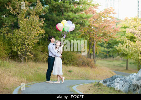 Sposa e lo sposo in piedi presso il parco con palloncini Foto Stock