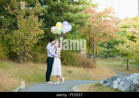 Sposa e lo sposo permanente al parco con palloncini Foto Stock