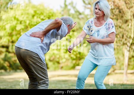 Senior donna aiuta l'uomo avente lombaggine dolore nel parco in estate Foto Stock