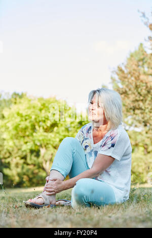 Senior donna con piede slogata con dolore nel parco Foto Stock