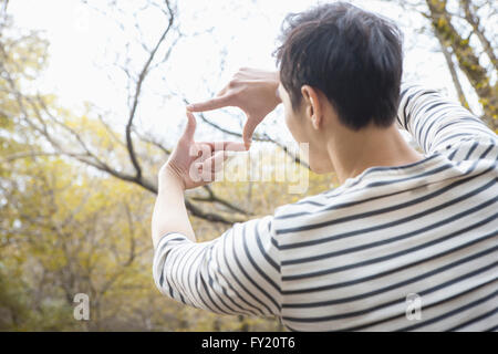 Uomo che fa un telaio con la sua mano e guardando attraverso di esso Foto Stock