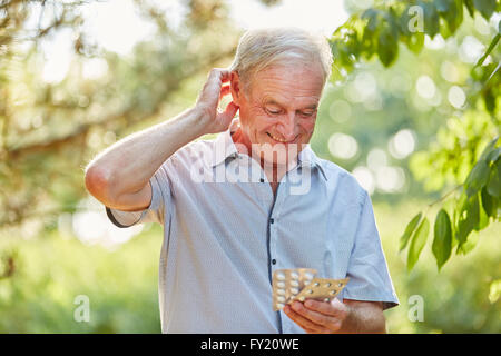 Senior dubbia l uomo con la medicina sulle sue mani nella natura Foto Stock