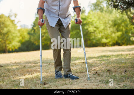 Il vecchio uomo a camminare sulle stampelle in natura in rehab Foto Stock