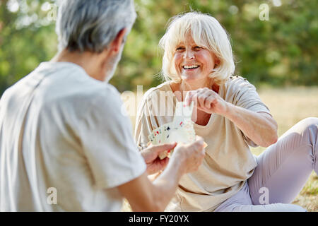 Felice coppia senior carte da gioco nel giardino in estate Foto Stock