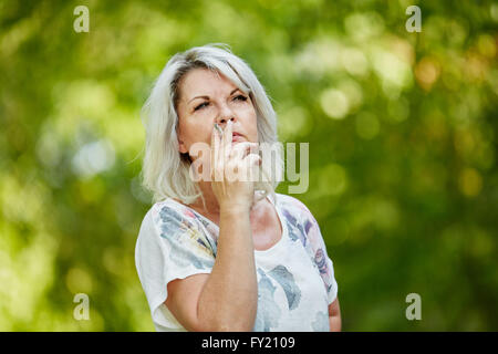 Donna senior di fumare una sigaretta per rilassarsi in estate Foto Stock