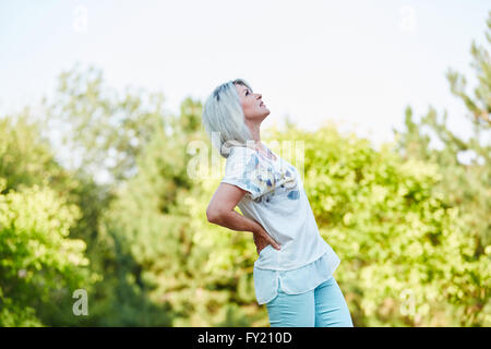 Senior donna avente lombaggine dolore nella natura in estate Foto Stock