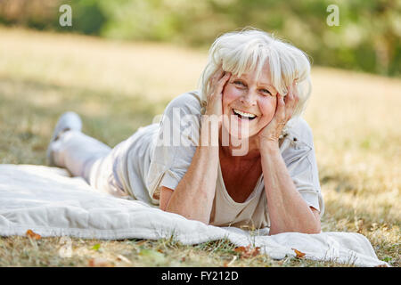 Sorridente vecchi pensionati lady posa sull'erba in estate la natura Foto Stock