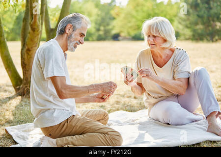 Coppia senior giocando a carte insieme in estate in giardino Foto Stock