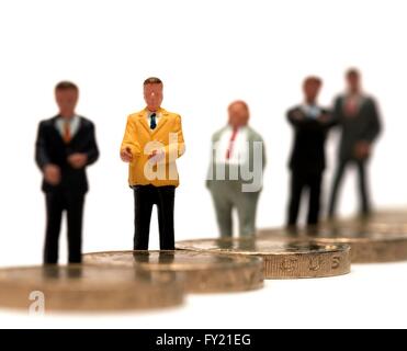 Un gruppo di figurine in miniatura di uomini di affari in piedi su alcuni britannici una libbra di monete Foto Stock