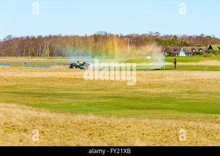 Skanor, Svezia - 11 Aprile 2016: lavoratore di sesso maschile di irrigazione è sul campo da golf ma il flessibile dell'acqua perde e diffondere l'acqua fino a Foto Stock