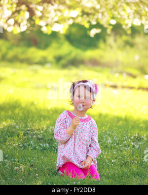 Bambino felice soffiando tarassaco all'aperto nel parco di primavera Foto Stock