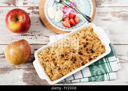 Apple Crumble dessert con fragole e panna alla vaniglia su luce rustico sfondo di legno Foto Stock