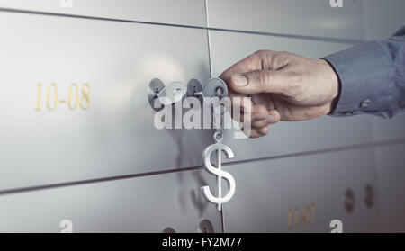 La cassetta di sicurezza in un caveau della banca, mano circa a sua volta una chiave per aprire una cassetta di sicurezza. concetto finanziario Foto Stock