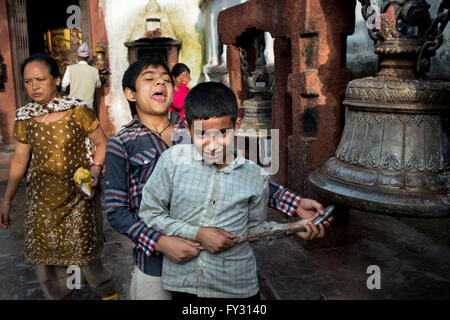 Bambini squillo campana gigante per celebrare il periodo del nuovo anno tibetano a Stupa Boudhanath, Kathmandu, Nepal. Foto Stock