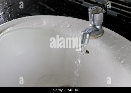 Rubinetto con acqua fluente nel lavandino. Foto Stock