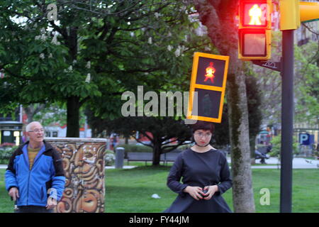 L'artista Kubra Khademi (Ghor, Afghanistan, 1989) ha girato le strade di Gijon semaforo mascherata per una performance dal titolo "Kubra e crosswalks III " con lo scopo di combattere il machismo. Sul suo capo che indossava una casella arancione, simulando un semaforo con due anse, compresi due bulbi, uno verde e uno rosso e sul loro due cartone nero con fori a forma di donna. Una donna con abito di criticare il machismo che sta dietro a un semaforo per utilizzando le figure pantaloni. Foto Stock