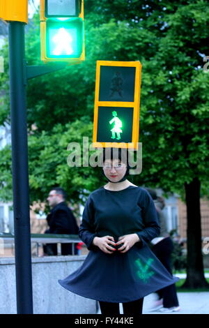 L'artista Kubra Khademi (Ghor, Afghanistan, 1989) ha girato le strade di Gijon semaforo mascherata per una performance dal titolo "Kubra e crosswalks III " con lo scopo di combattere il machismo. Sul suo capo che indossava una casella arancione, simulando un semaforo con due anse, compresi due bulbi, uno verde e uno rosso e sul loro due cartone nero con fori a forma di donna. Una donna con abito di criticare il machismo che sta dietro a un semaforo per utilizzando le figure pantaloni. Foto Stock