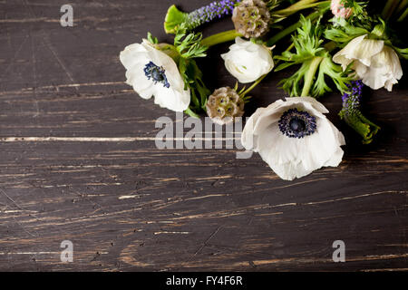 Anemoni bianchi e bianco renoncules giacente sul vecchio, legno scuro in alto a destra Foto Stock