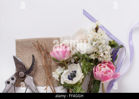 Tulipani rosa, anemoni bianchi, bianco renoncules e prugna Fiore di ramo di albero giacente su bianco dalla parte superiore con nastro e la potatura s Foto Stock