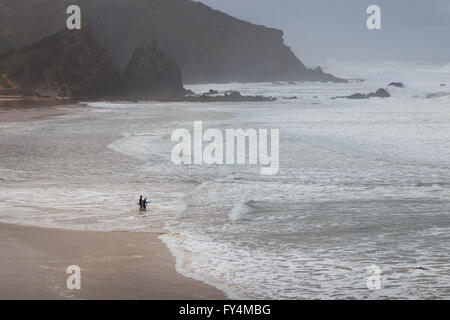 Due surfer il loro modo nell'Oceano Atlantico sulla spiaggia "Praia do amado', Portogallo. Foto Stock