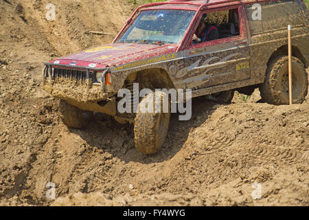Red off-road auto su un ripido pendio nel terreno fangoso Foto Stock